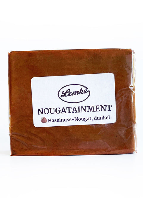 Ein Block dunkles Haselnuss-Nougat von Lemke mit der Aufschrift "Nougatainment". Hochwertiges Nougat, ideal für Pralinen, Desserts und Backwaren. Perfekt für professionelle Anwendungen und Feinschmecker.