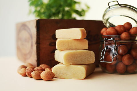 Ein Stapel von Lemke Marzipan Rohmasse Blšcken neben einem Glas voller Marzipankartoffeln und losen Mandeln. Ein Hauch von frischem GrŸn im Hintergrund rundet das Bild ab.
